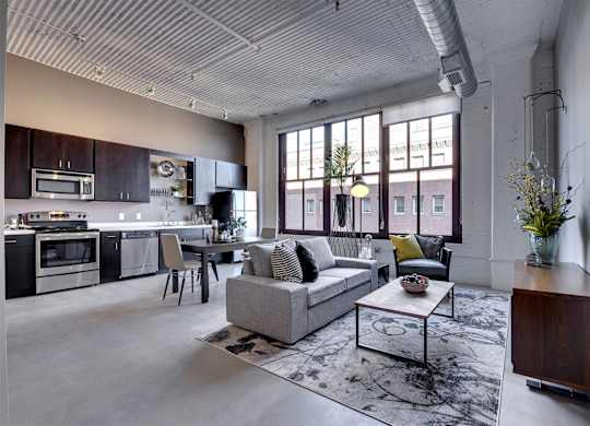 A modern open plan living and kitchen area with a grey sofa and a coffee table.