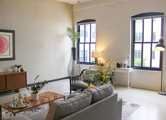 A living room with a grey couch and a coffee table with a vase of flowers on it.