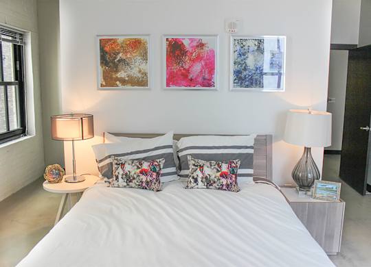 A bedroom with a large bed and two lamps.