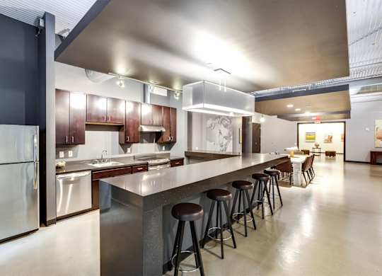 A modern kitchen with a long counter and stools.