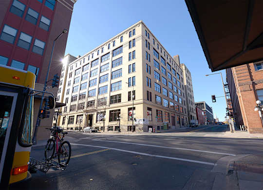 A city street with a bus, a bicycle, and a tall building.