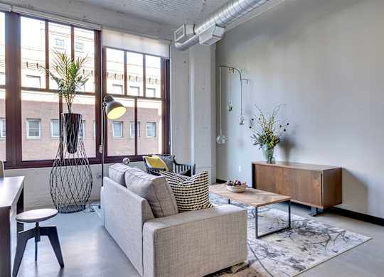 A living room with a couch, a chair, a table, and a vase with flowers.