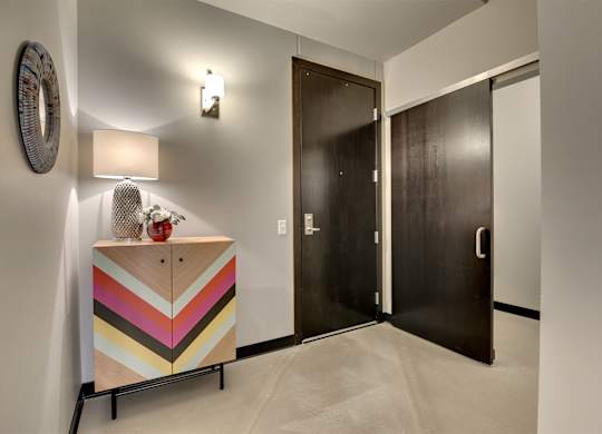 A wooden cabinet with a chevron pattern painted in pastel colors sits in a hallway.