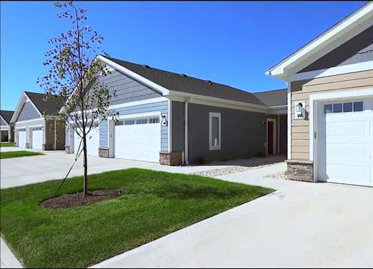 A house with a white garage door and a tree in front.