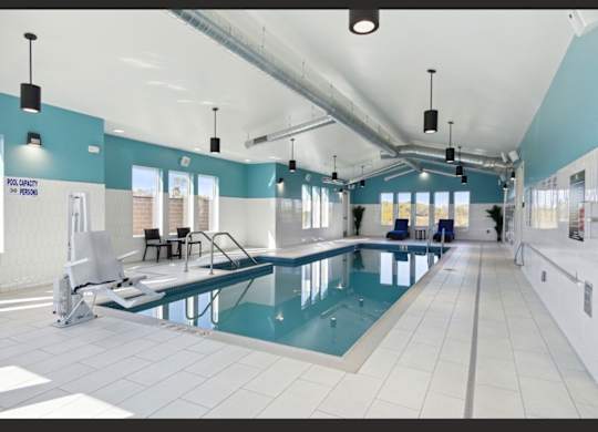 A large indoor swimming pool with a diving board and lane markers.