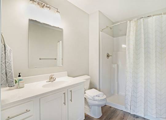 A white bathroom with a toilet, sink, and shower.