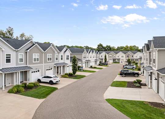 A row of houses with cars parked in front.