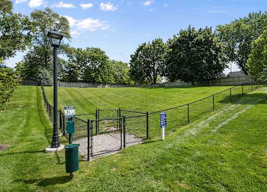 A green sign is on a pole in a grassy area.