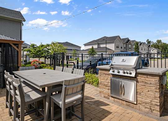 A patio with a table, chairs and a grill.