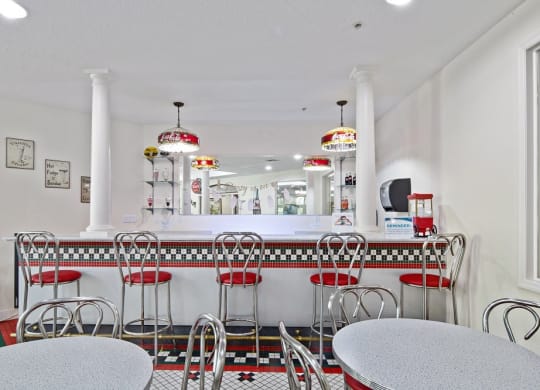 a diner with red and white chairs and a white counterat Arbor Oaks at Greenacres, Florida, 33467
