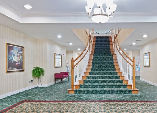 a large staircase with a chandelier at the top at Arbor Oaks at Greenacres, Florida