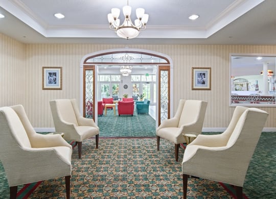a room with chairs and a chandelier and a table in the backgroundat Arbor Oaks at Greenacres, Greenacres, 33467