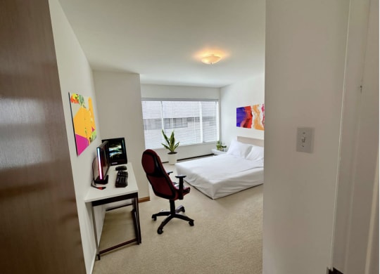 a bedroom with a bed and a desk in a room