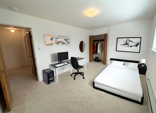 a bedroom with a bed and a desk in a room