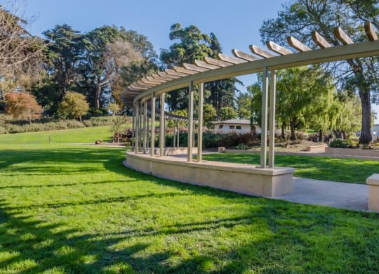 a pergola in a park with a playground in the background