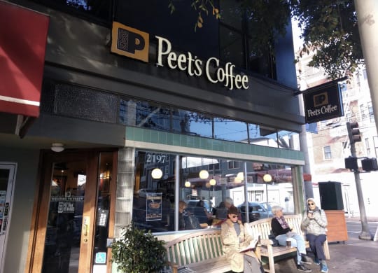 people sitting on a bench in front of a coffee shop