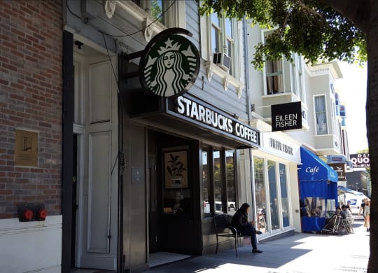 a person sitting in a chair in front of a starbucks coffee shop on a city street