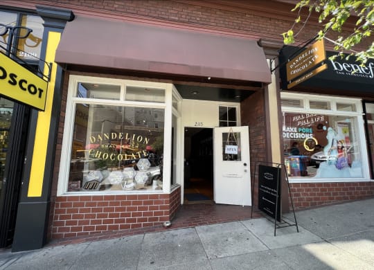 a brick building with a white door and a window with a sign that reads dandelion