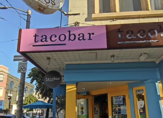 a taco bar with a pink sign in front of it