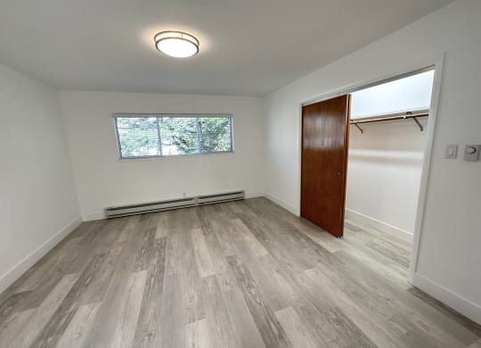 a bedroom with hardwood floors and white walls