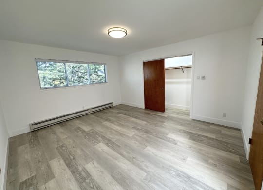 a bedroom with hardwood floors and white walls