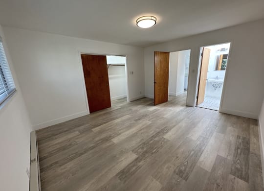 a bedroom with hardwood floors and white walls