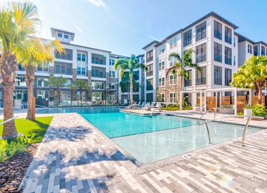 Resort-style pool with expansive sundeck and pergolas at at Tapestry Nona Apartments in Orlando, FL