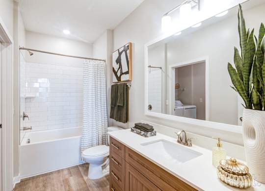 A bathroom with a white tub/shower combo, quartz countertops, and undermount sinks at Tapestry Nona in Orlando, FL