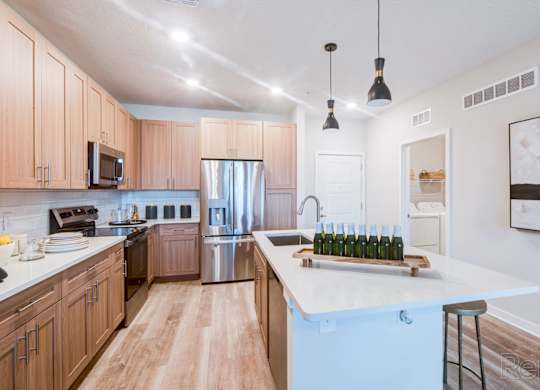 A kitchen with wooden cabinets and a white quartz island at Tapestry Nona in Orlando, FL