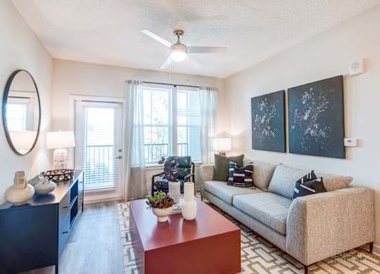 A living room with ceiling fan and private balcony/patio access at Tapestry Nona in Orlando, FL