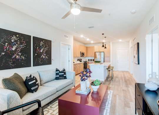 A living room with a couch, a table, and a ceiling fan at Tapestry Nona in Orlando, FL