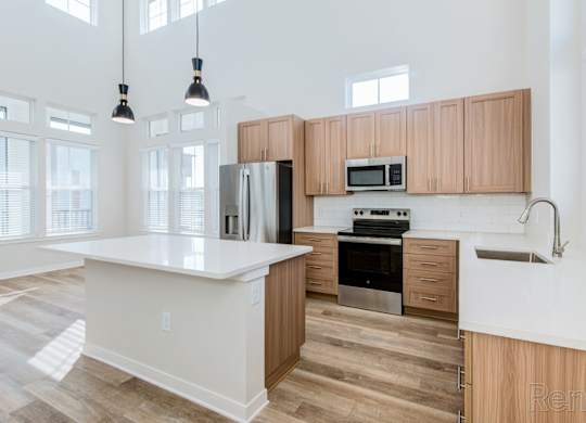 Island kitchen with natural light, quartz countertops, and undermount sink at Tapestry Nona Apartments in Orlando, FL