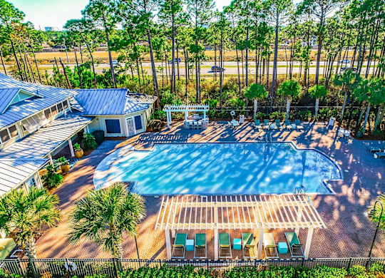 A large swimming pool surrounded by a fence and palm trees.