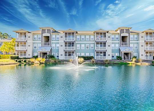 A large apartment complex with a fountain in front.