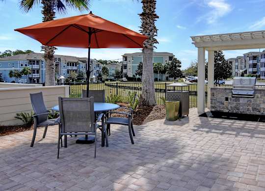 A patio with a table, chairs and an umbrella.