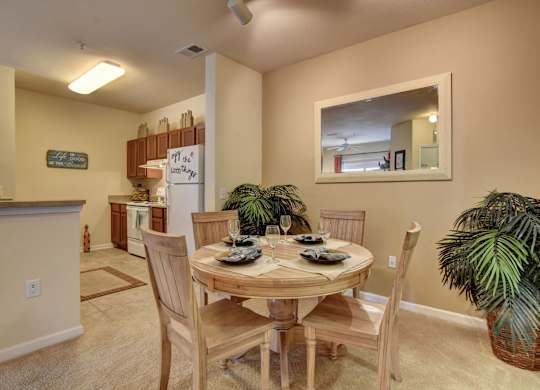 A dining room with a table set for two and a potted plant.
