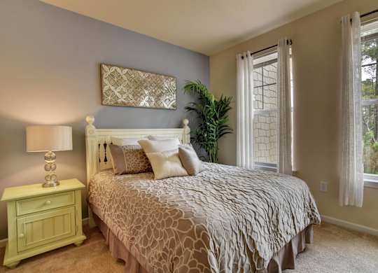 A bedroom with a bed, nightstand, and window.