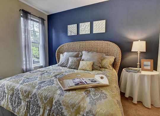 A bed with a yellow and grey comforter is in a room with blue walls.