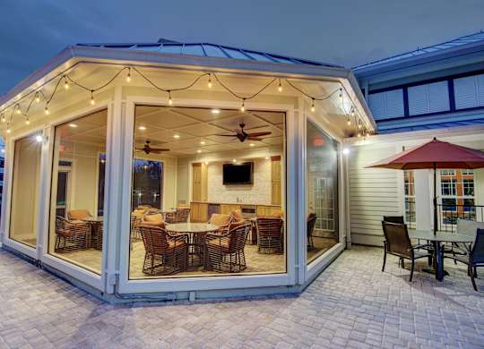 A patio with a table and chairs is lit up with string lights.