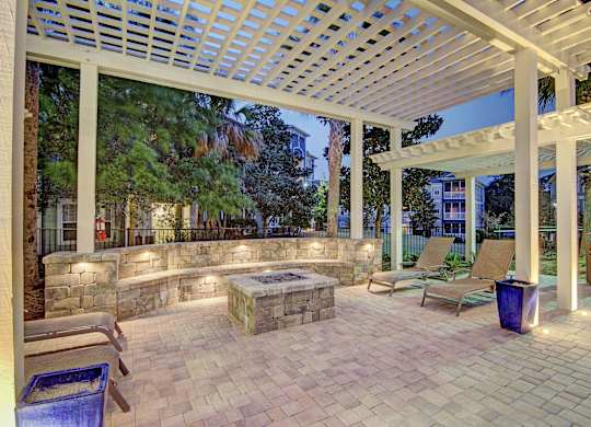 A patio with a white pergola and a stone wall.