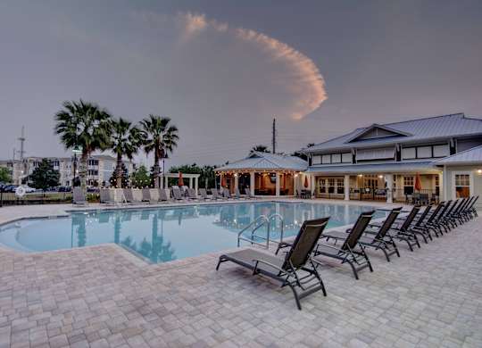 A swimming pool surrounded by lounge chairs and palm trees.