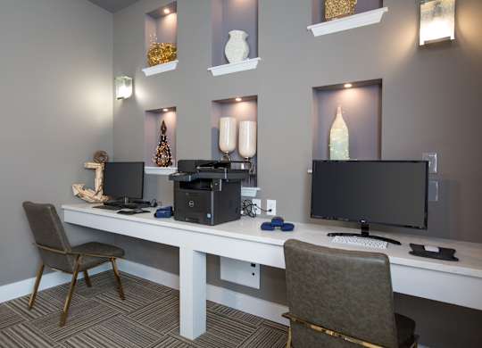 A modern home office with a desk, chairs, and computer equipment.