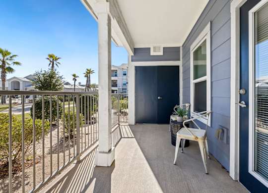 A balcony with a chair and table on a sunny day.