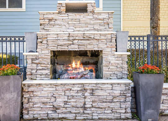 A stone fireplace with a fire burning inside.