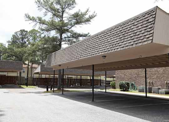 A parking lot with a long covered parking area The Oakley at Hillcrest in Mobile, AL.