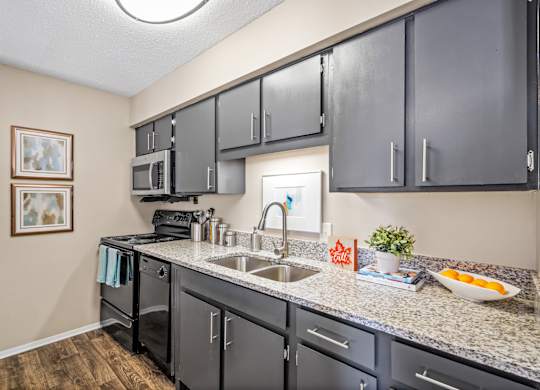 a kitchen with granite counter tops and dark cabinets at 701 South Apartments in Mobile, AL