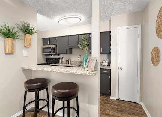 A kitchen with a white countertop and brown stools.