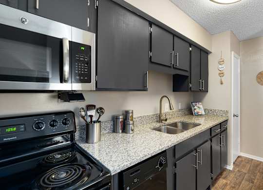 A kitchen with black cabinets and a stove top oven.