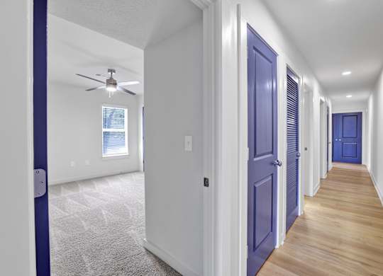 a hallway with blue doors and a ceiling fan