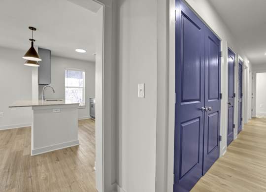 a hallway with blue doors leading to a kitchen and a counter top in a house